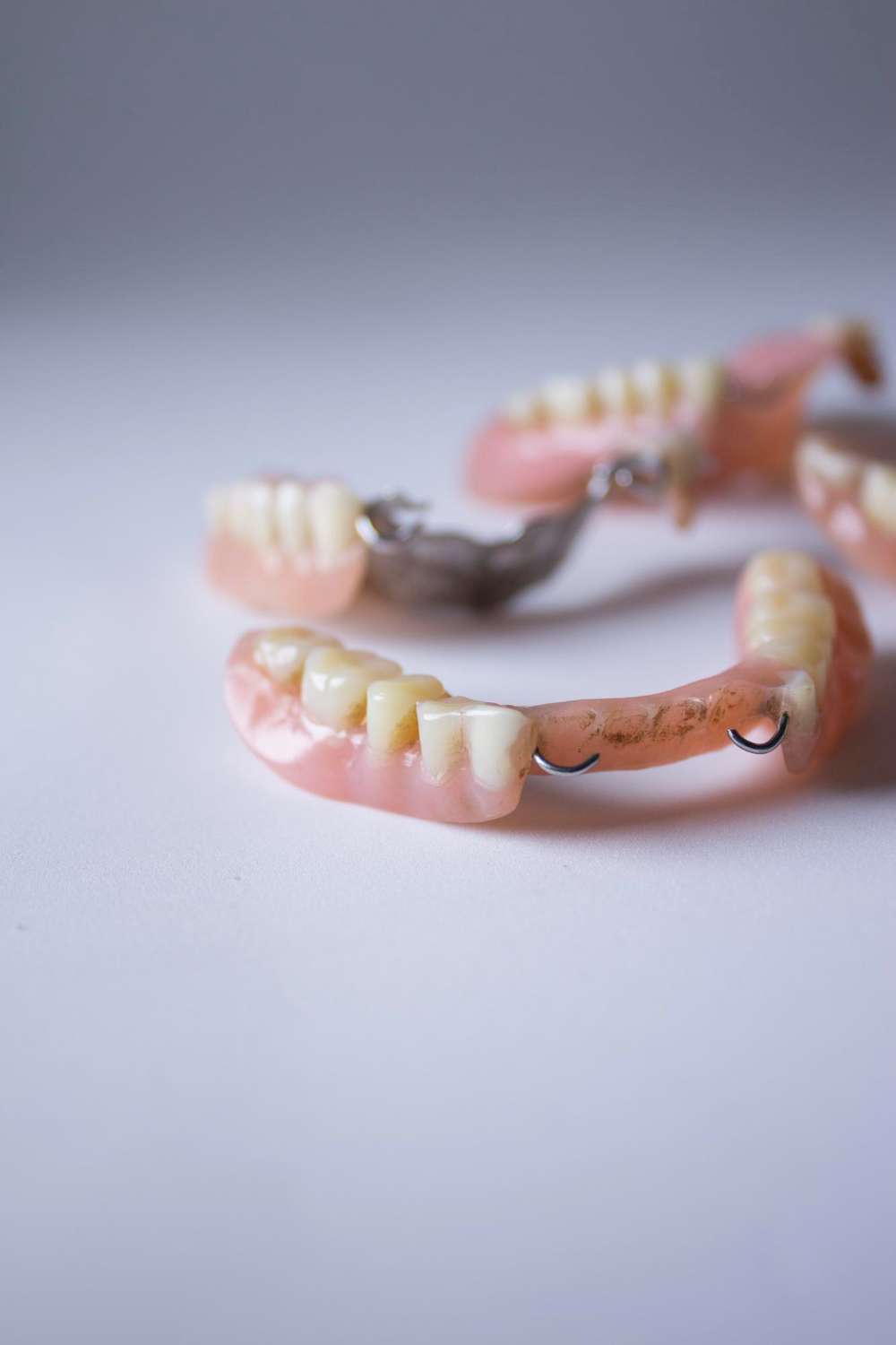 Un conjunto de prótesis parciales con encías rosas y dientes artificiales expuestos sobre una superficie blanca en una clínica dental Moratalaz. de Hospital Dental de Moratalaz "Martínez y Morcuende"