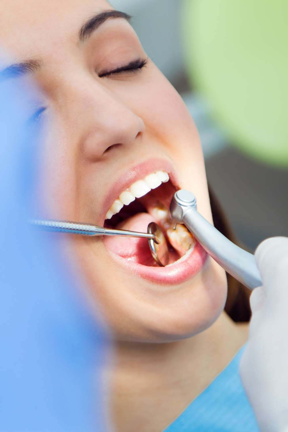 Una persona en la clínica dental Moratalaz con la boca abierta, recibiendo un examen dental o una limpieza con instrumentos dentales. de Hospital Dental de Moratalaz "Martínez y Morcuende"
