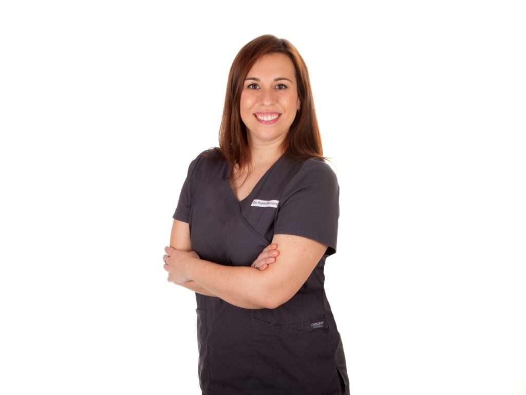 Mujer de pelo castaño liso, con bata médica oscura, sonriendo con confianza: su dentista de confianza en Moratalaz. de Hospital Dental de Moratalaz "Martínez y Morcuende"